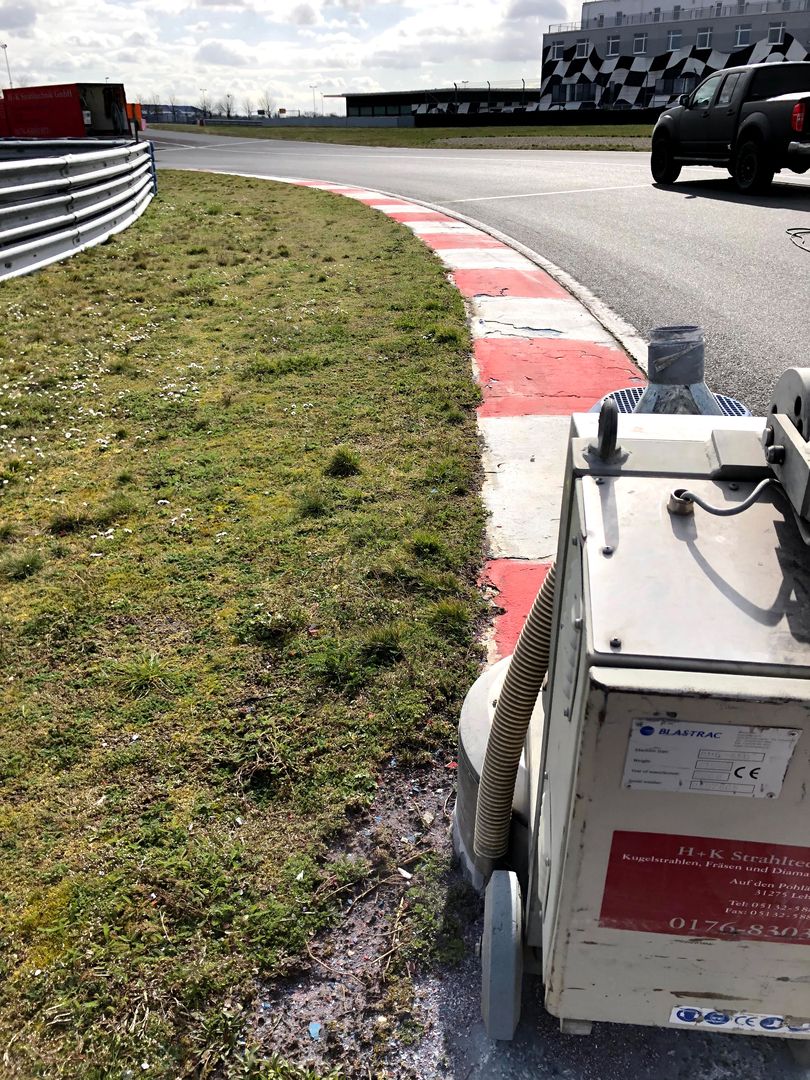 Die Farbahnmarkierung einer Rennstrecke wird abgeschliffen